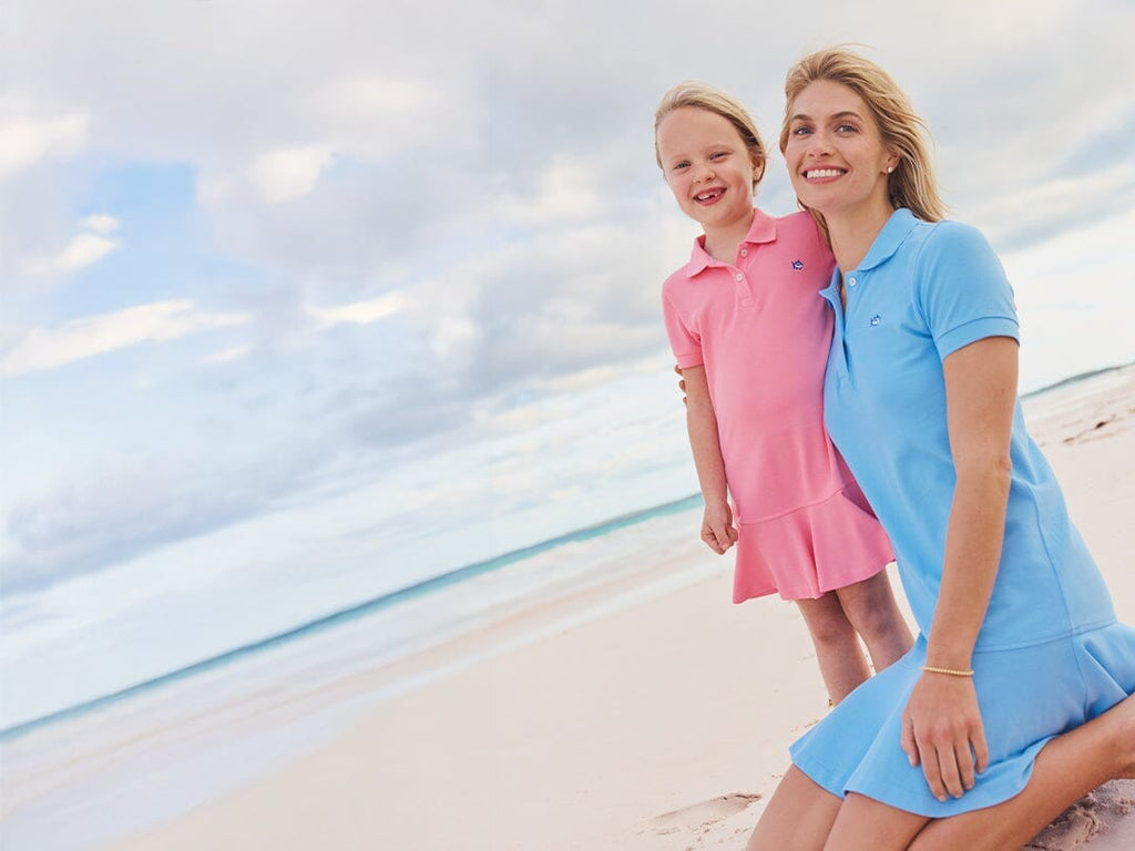 Woman in blue polo dress with girl in pink polo dress.