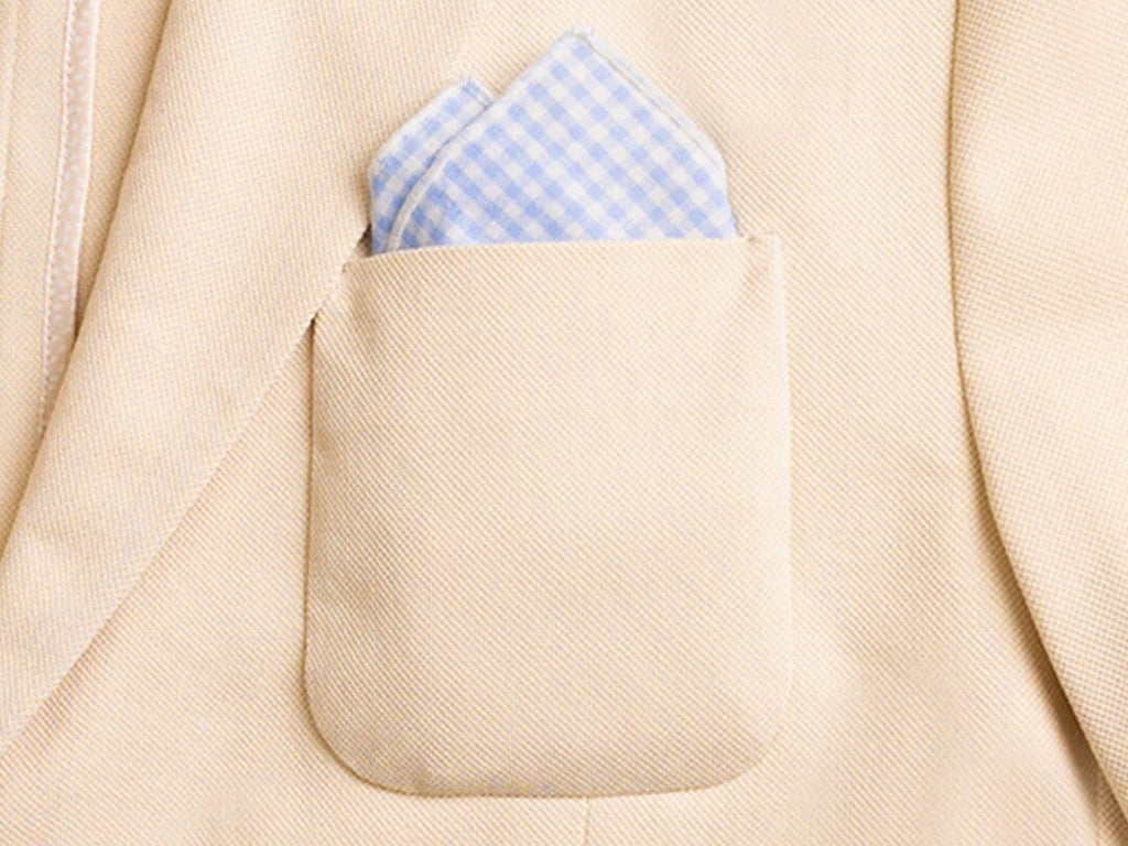 Blue and white gingham pocket square, folded with the two point fold method, in the pocket of a pale khaki blazer.
