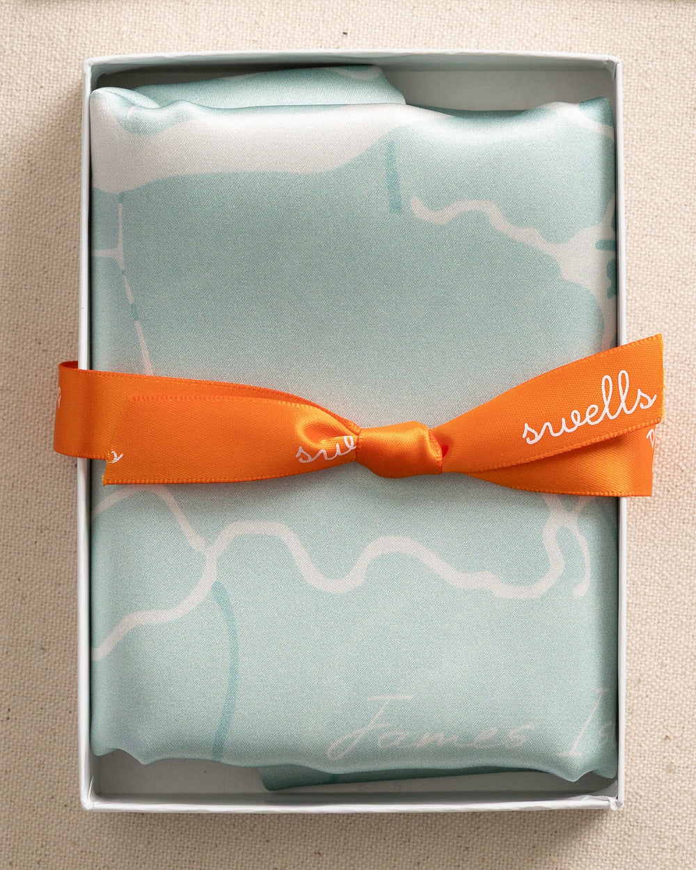 The front packaging view of the Southern Tide Swells Aerial Map Scarf by Southern Tide - Teal