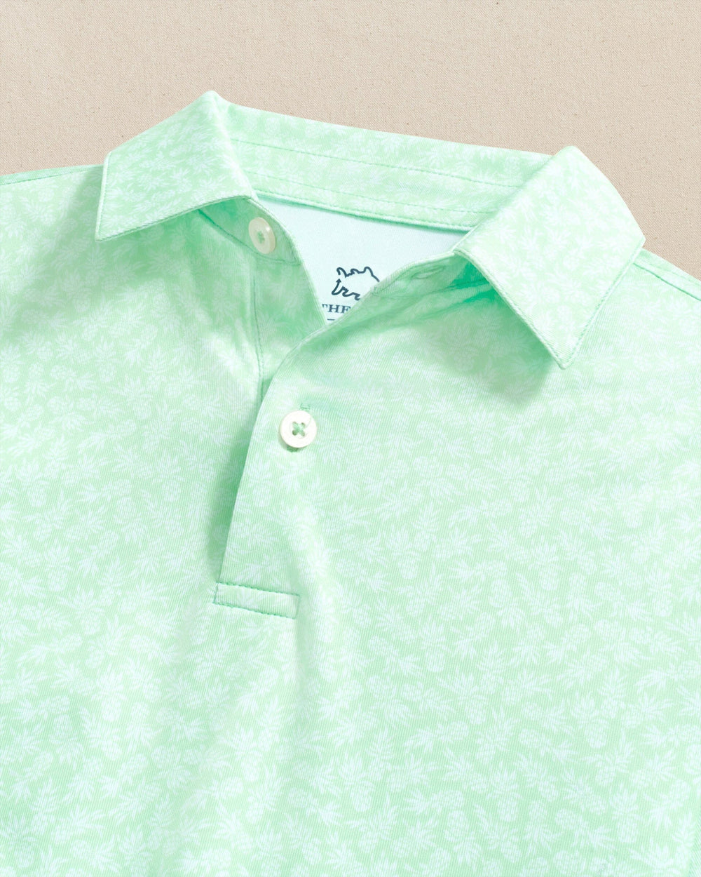 The detail view of the Southern Tide Boys Driver Pineapple Parade Printed Performance Polo by Southern Tide - Green Ash