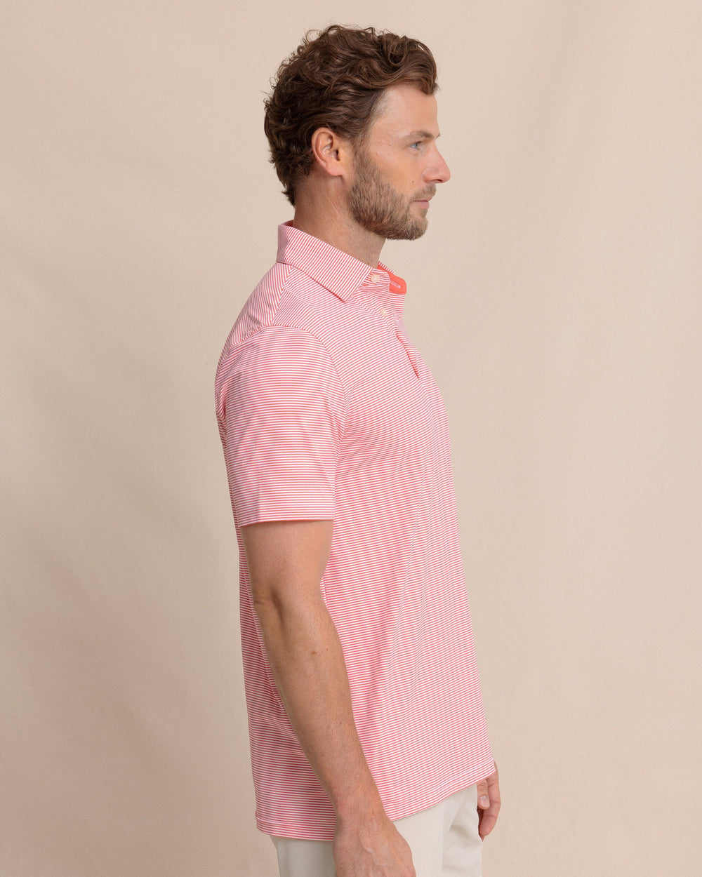 The side view of the Southern Tide brrr°®-eeze Meadowbrook Stripe Polo by Southern Tide - Sunkist Coral