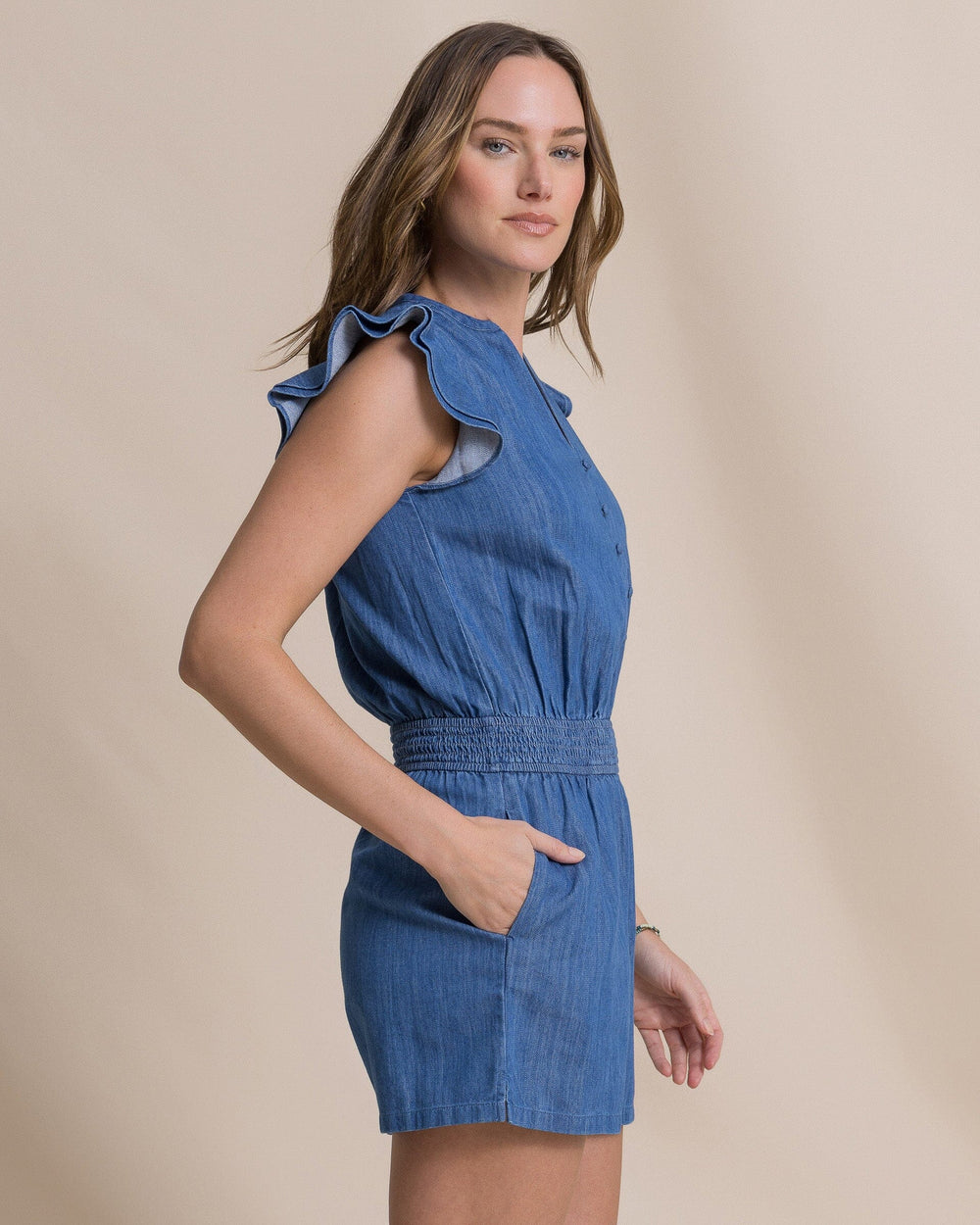 The side view of the Southern Tide Evalyn Flutter Sleeve Smocked Romper by Southern Tide - Medium Wash Indigo