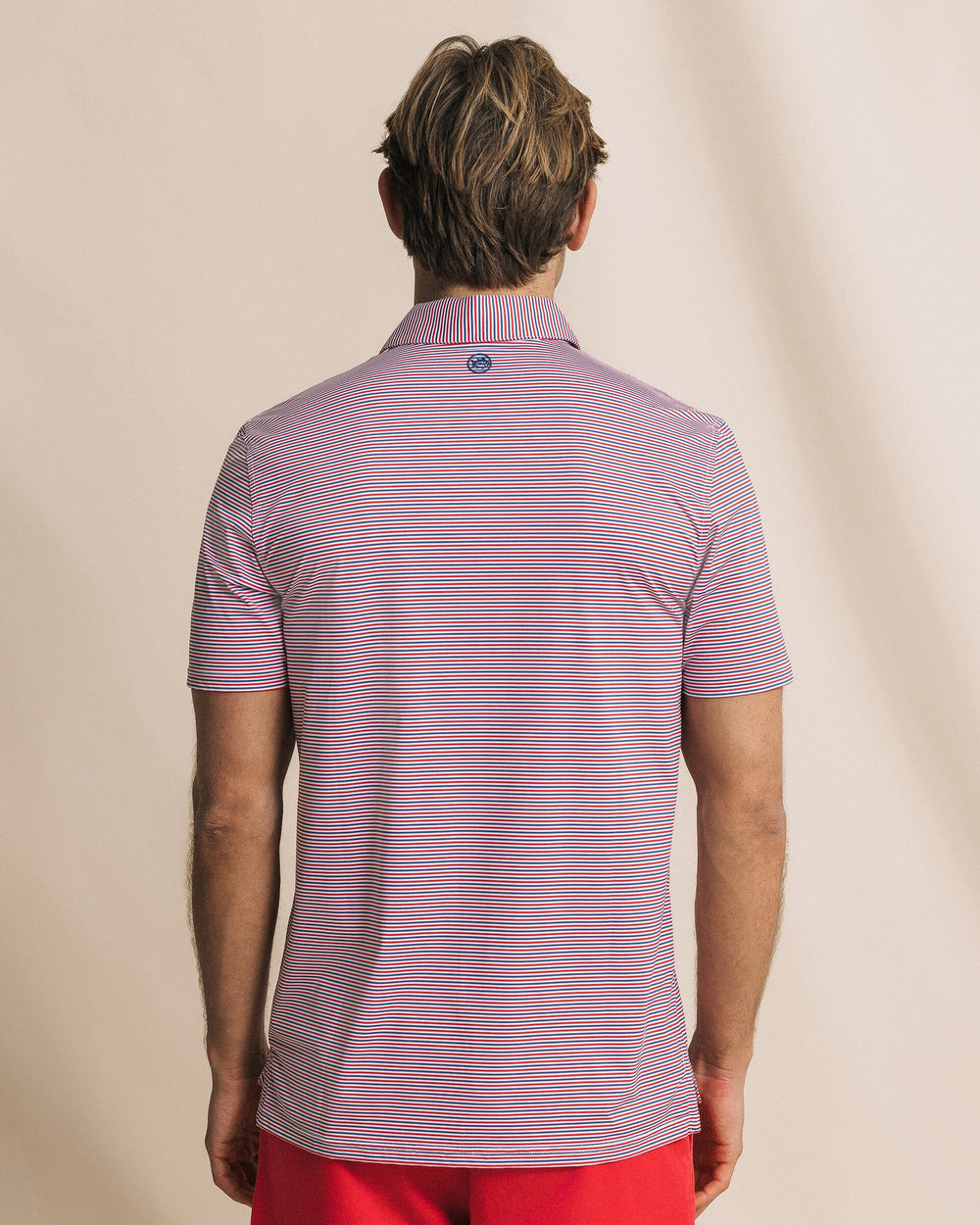 The back view of the Southern Tide Pelican Landing Stripe Coastal Breeze® Performance Polo by Southern Tide - Channel Marker Red