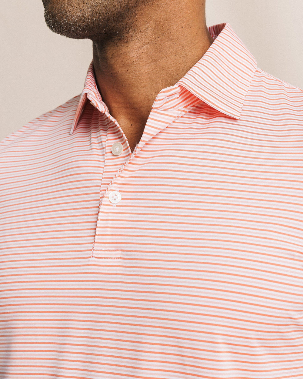 The detail view of the Southern Tide Pelican Landing Stripe Coastal Breeze® Performance Polo by Southern Tide - Orange Blossom