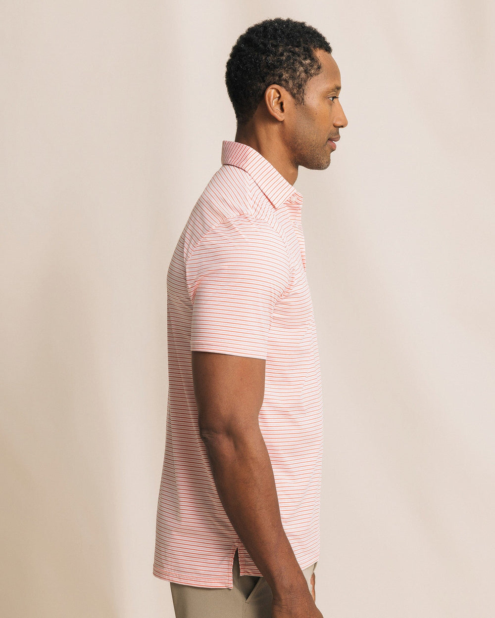 The side view of the Southern Tide Pelican Landing Stripe Coastal Breeze® Performance Polo by Southern Tide - Orange Blossom